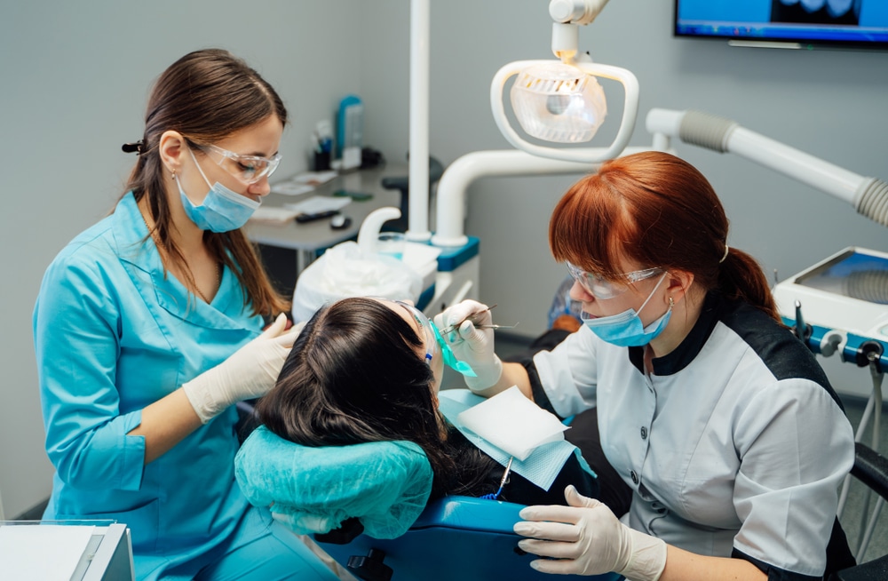 two women in a dental office cleaning a patient's teeth